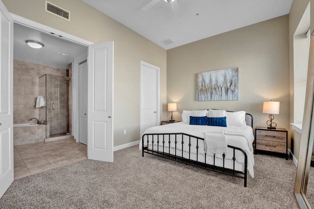 A bedroom with a large bed and a painting on the wall.