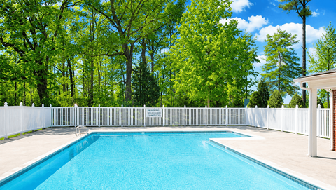 A swimming pool surrounded by a white fence and trees.