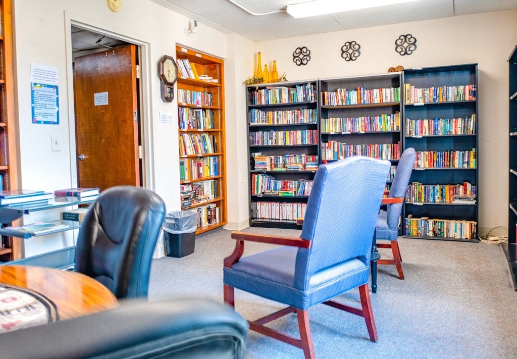a library with three blue chairs and three bookshelves