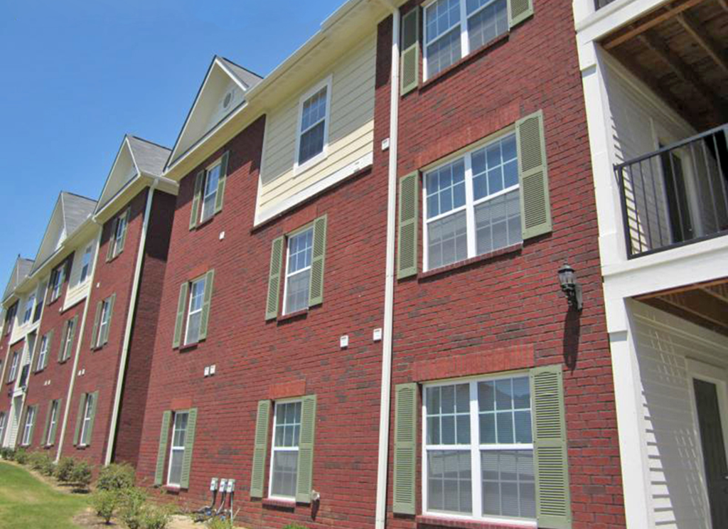 a red brick apartment building with green shutters