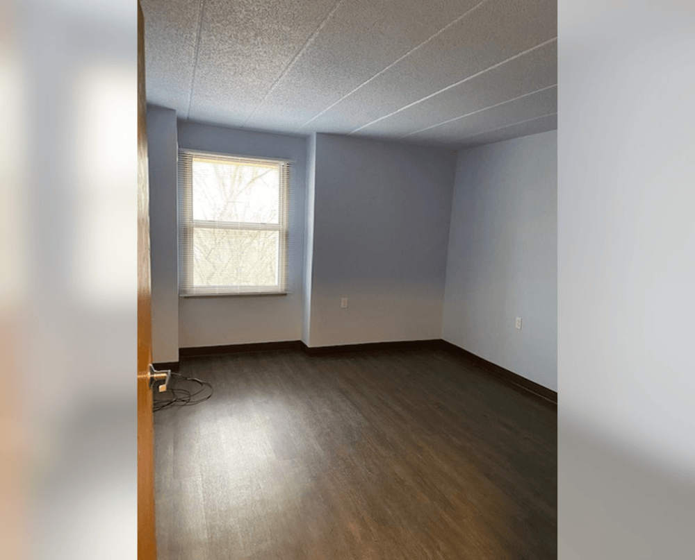 an empty room with wood floors and a window