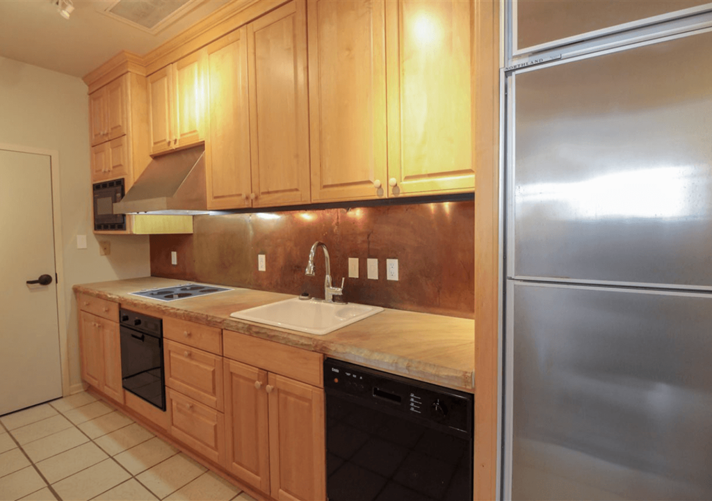 A kitchen with wooden cabinets and a stainless steel refrigerator.