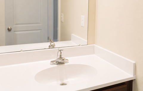 A white sink in a bathroom with a mirror above it.