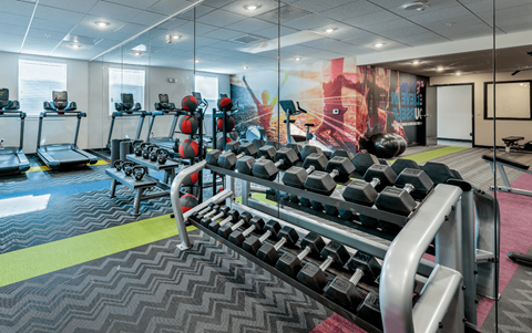a gym with weights and cardio equipment in a room with glass walls