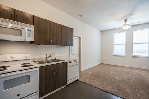 A kitchen with white appliances and brown cabinets.
