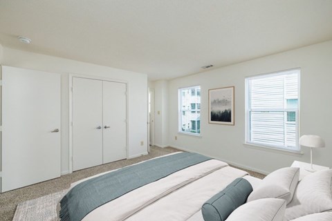 A bedroom with a large bed and a window with blinds.