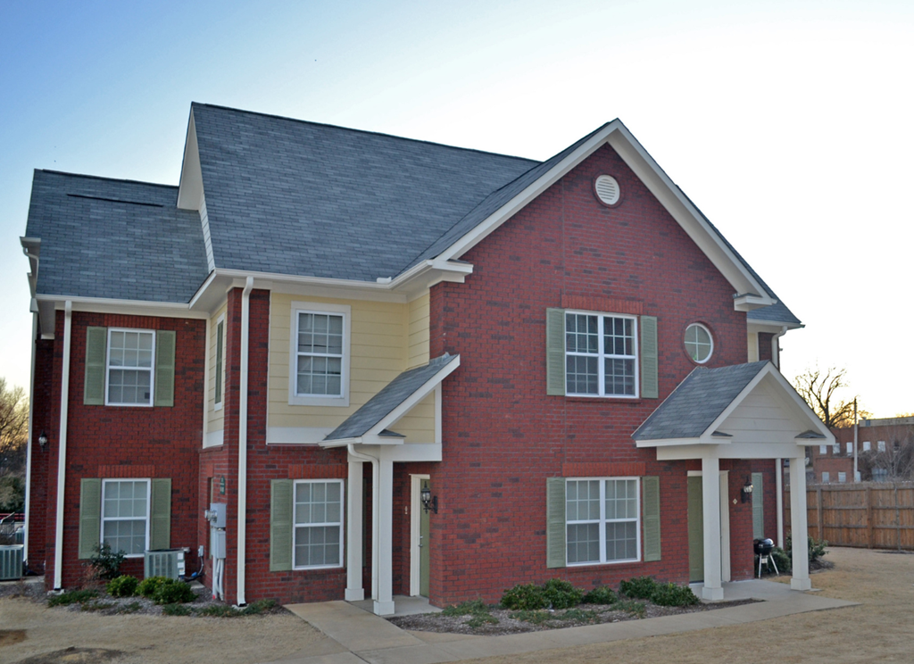 a red brick house with white pillars and a gray roof