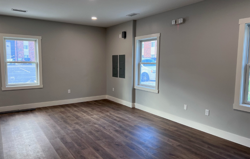 an empty living room with wood floors and grey walls