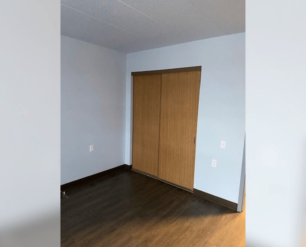 an empty room with wood floors and a door to a closet