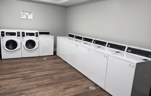 a row of washers and dryers in a laundry room with wood floors