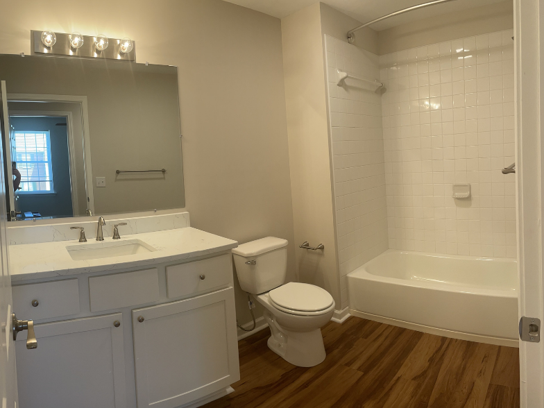 a bathroom with white fixtures and a wooden floor