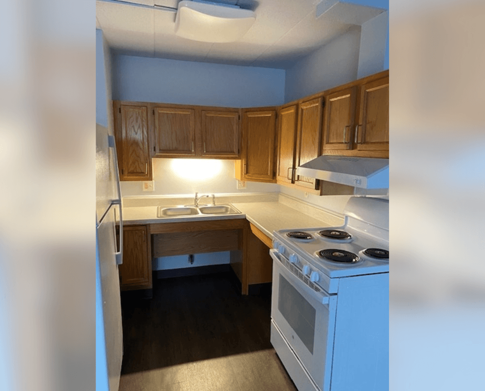 an empty kitchen with wood cabinets and white appliances