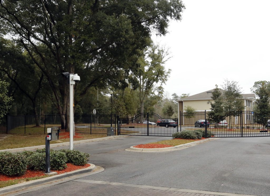 the entrance to a neighborhood with a black fence and gate