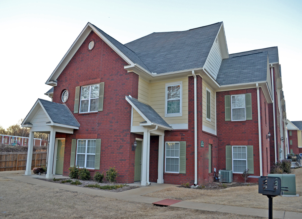 the front of a red brick house with a black roof