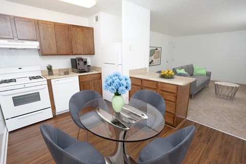 A modern kitchen with a glass table and grey chairs.