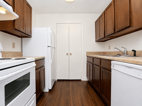 A kitchen with white appliances and brown cabinets.