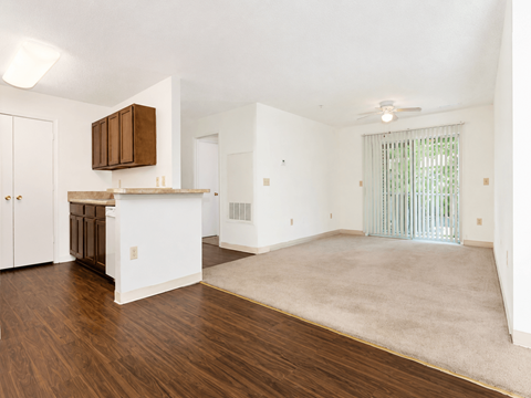 A spacious living room with a kitchen area in the background.