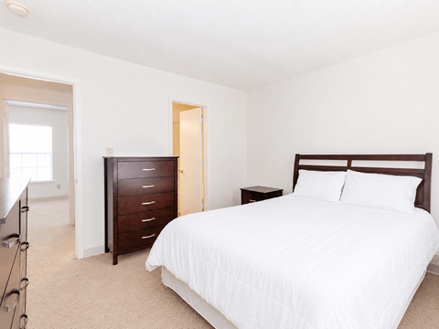 A bedroom with a large bed and a dresser.