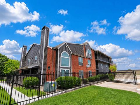 A large brick house with a black fence in front.
