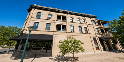 A large building with a black awning and a tree in front of it.