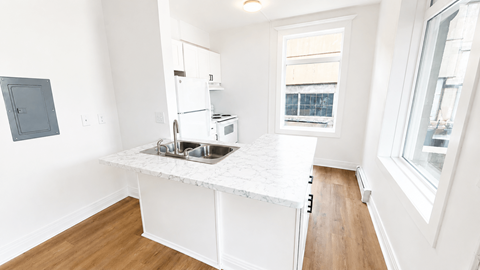 A kitchen with white cabinets and a window.