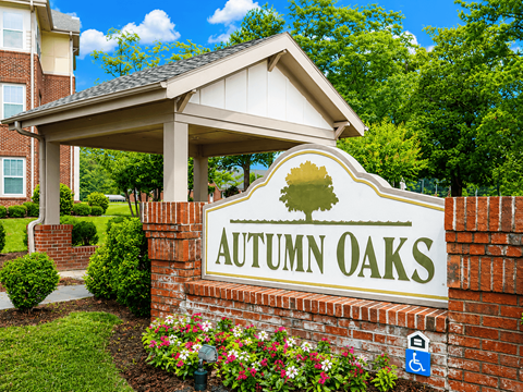 A sign that says Autumn Oaks in front of a building.