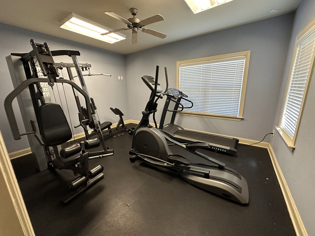 the gym has plenty of exercise equipment and a ceiling fan