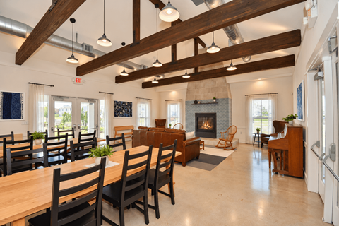 A clubhouse with large dining room with wooden chairs and a fireplace.