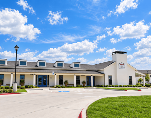 A white building with a sign on it and a blue sky with clouds.