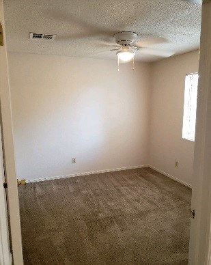an empty room with a ceiling fan and a carpet
