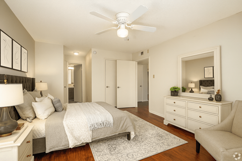 A bedroom with a bed, dresser, mirror, and ceiling fan.