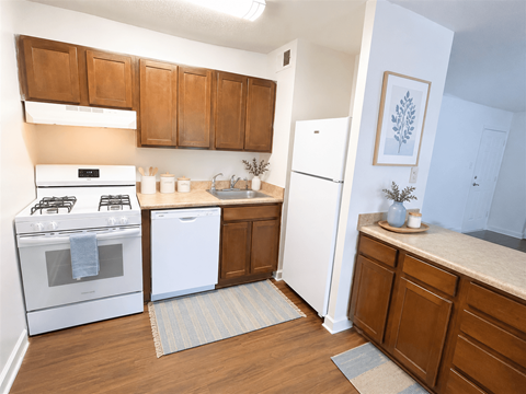 A kitchen with white appliances and wooden cabinets.