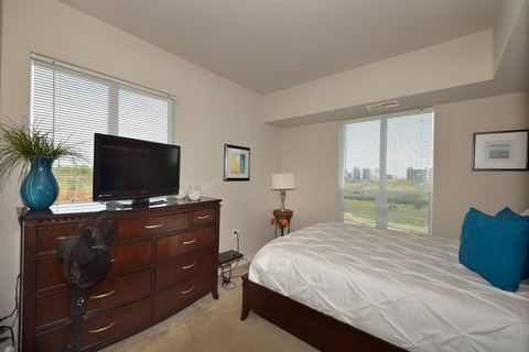A bedroom with a bed, dresser, and a television.