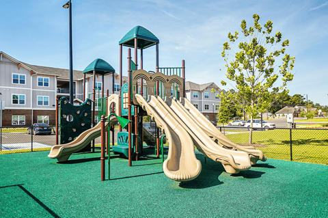 A playground with a green slide and a tree.