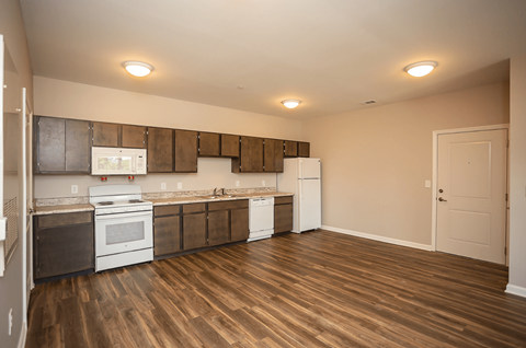 A kitchen with white appliances and wooden floors.
