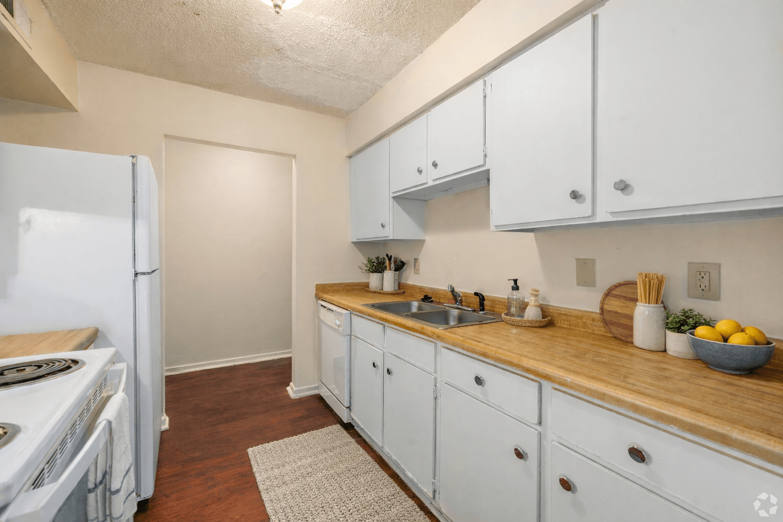 A kitchen with white cabinets and a wooden counter top.