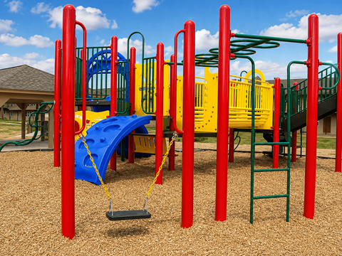 A playground with a blue slide and red and yellow play equipment.