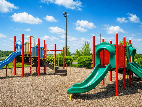 A playground with a green slide and a red and blue structure.