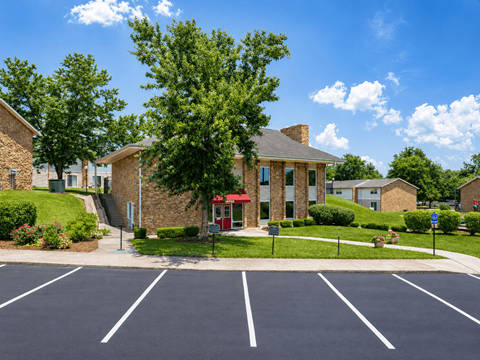 A parking lot in front of a building with a red awning.