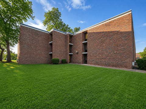 A red brick building with a green lawn in front.