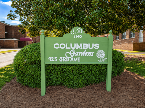 A green sign that says Columbus Gardens on it.