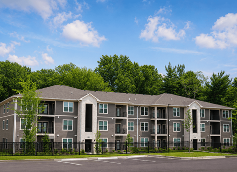 A large apartment building with a black fence in front.
