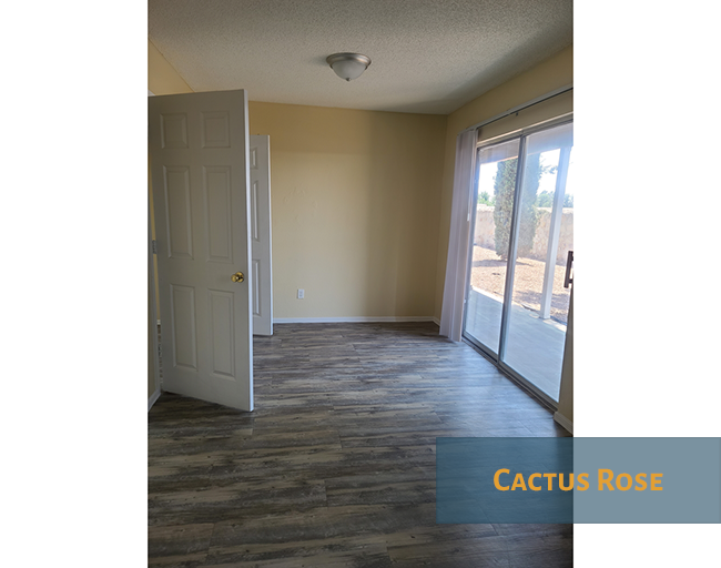 A room with a door and a window with a view of a backyard.