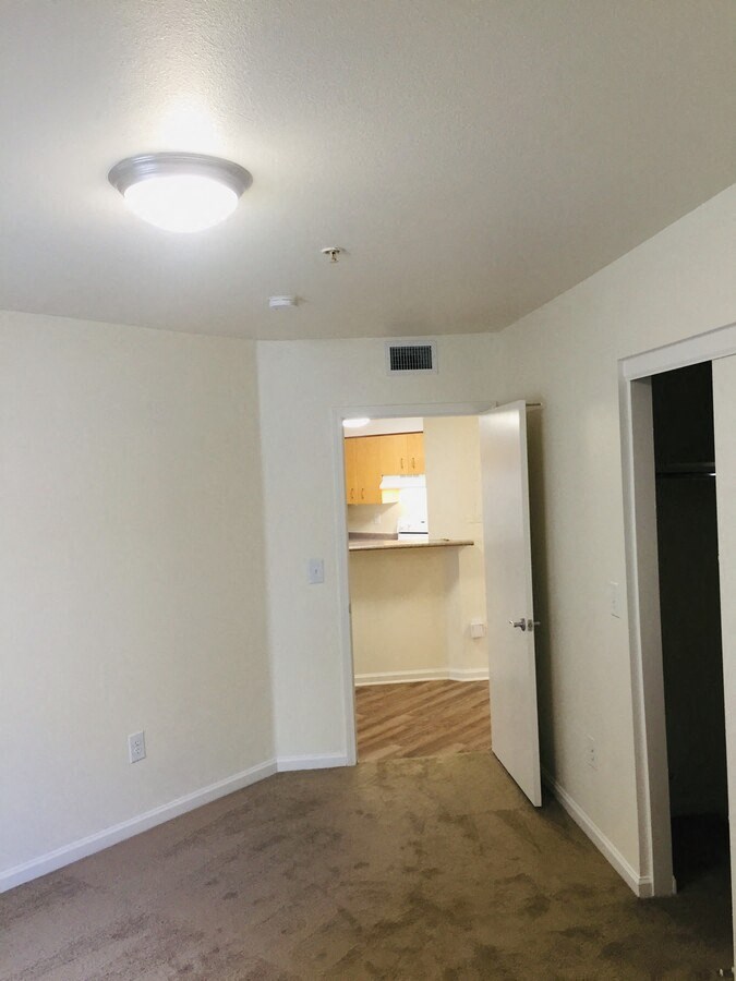 an empty living room with a door to a kitchen