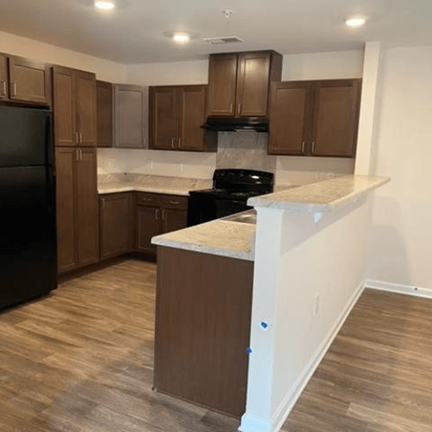 A kitchen with brown cabinets and a black refrigerator.