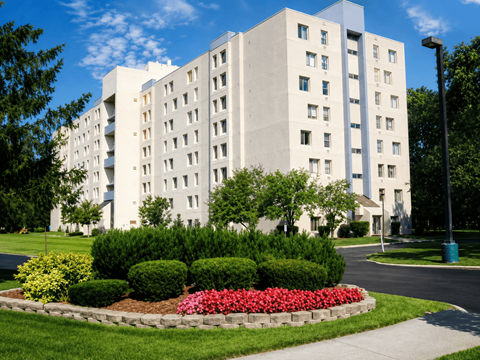 A large white building with a flower bed in front.