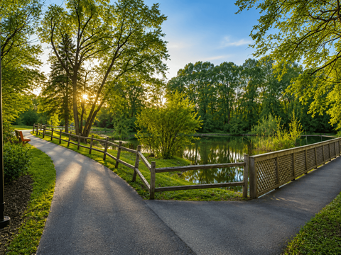 A paved road leads to a wooden bridge over a body of water.