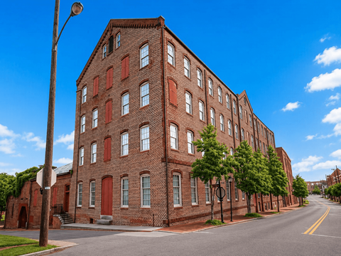 A long red brick building with many windows sits on a street corner.