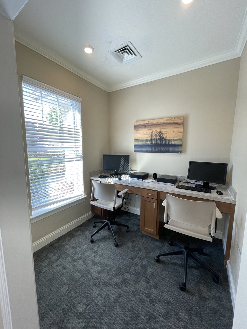 an office with two desks and two computers and a window