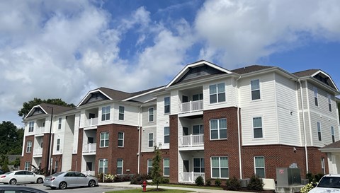 a brick and white apartment building with cars parked in front
